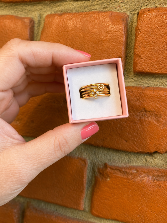 Five-piece gold heart stacking ring set displayed in a blush pink gift box
